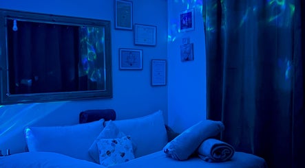 Serene massage room at Bee Elevated Holistic Health in Holbury, England, GB with calming blue lighting.