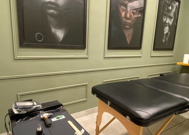 Interni eleganti di Iago Tattoo a Marano Di Napoli, Campania, IT con lettino nero e quadri artistici.