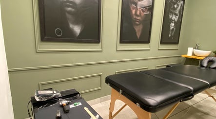 Interni eleganti di Iago Tattoo a Marano Di Napoli, Campania, IT con lettino nero e quadri artistici.
