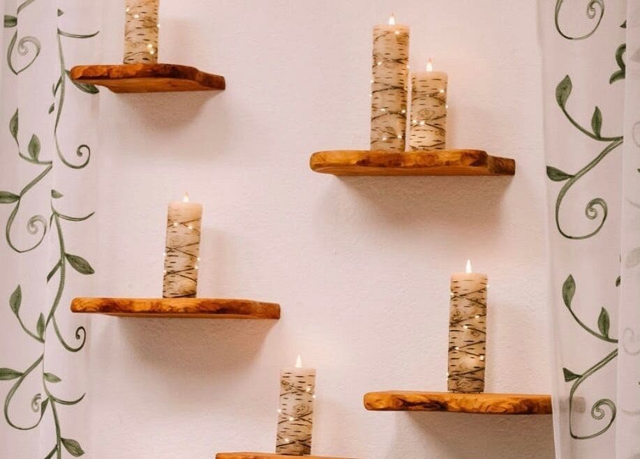 Decorative candles on wooden shelves at Scratched in Modesto, California, US, creating a serene ambiance.