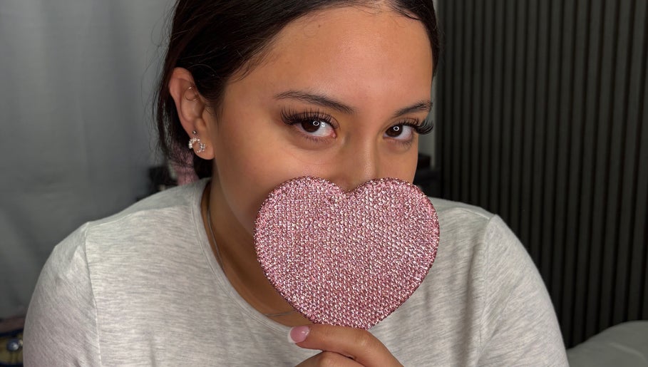 Woman holding a pink heart at Jiribeauty in Rockwall, Texas, US, showcasing eye-catching lashes.