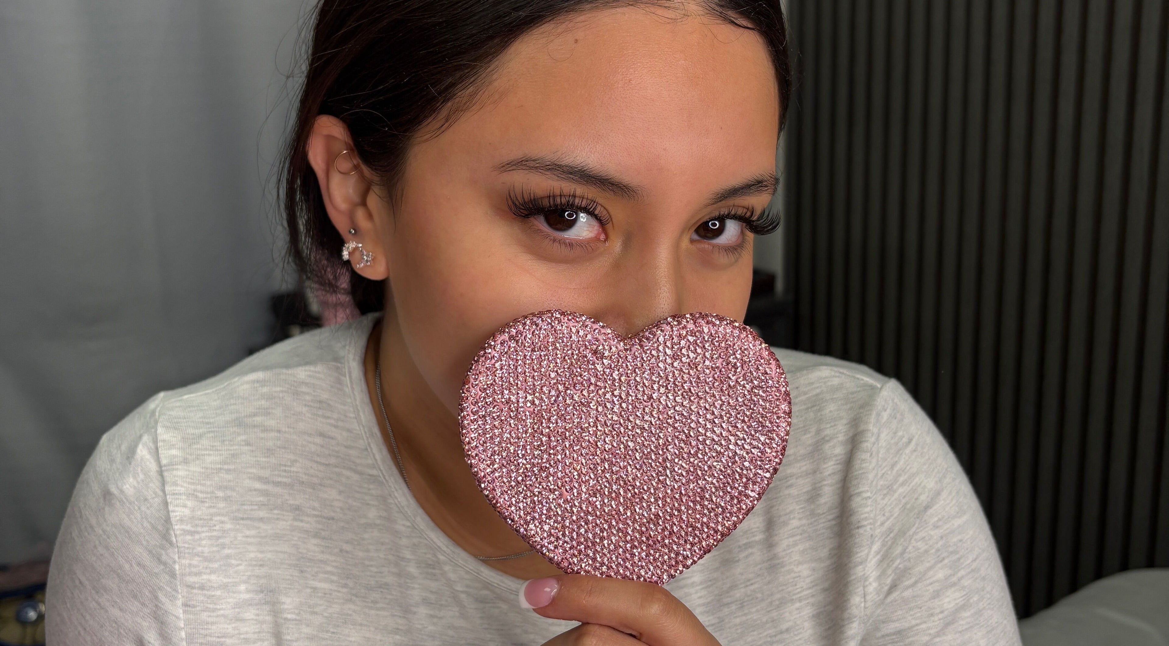 Woman holding a pink heart at Jiribeauty in Rockwall, Texas, US, showcasing eye-catching lashes.