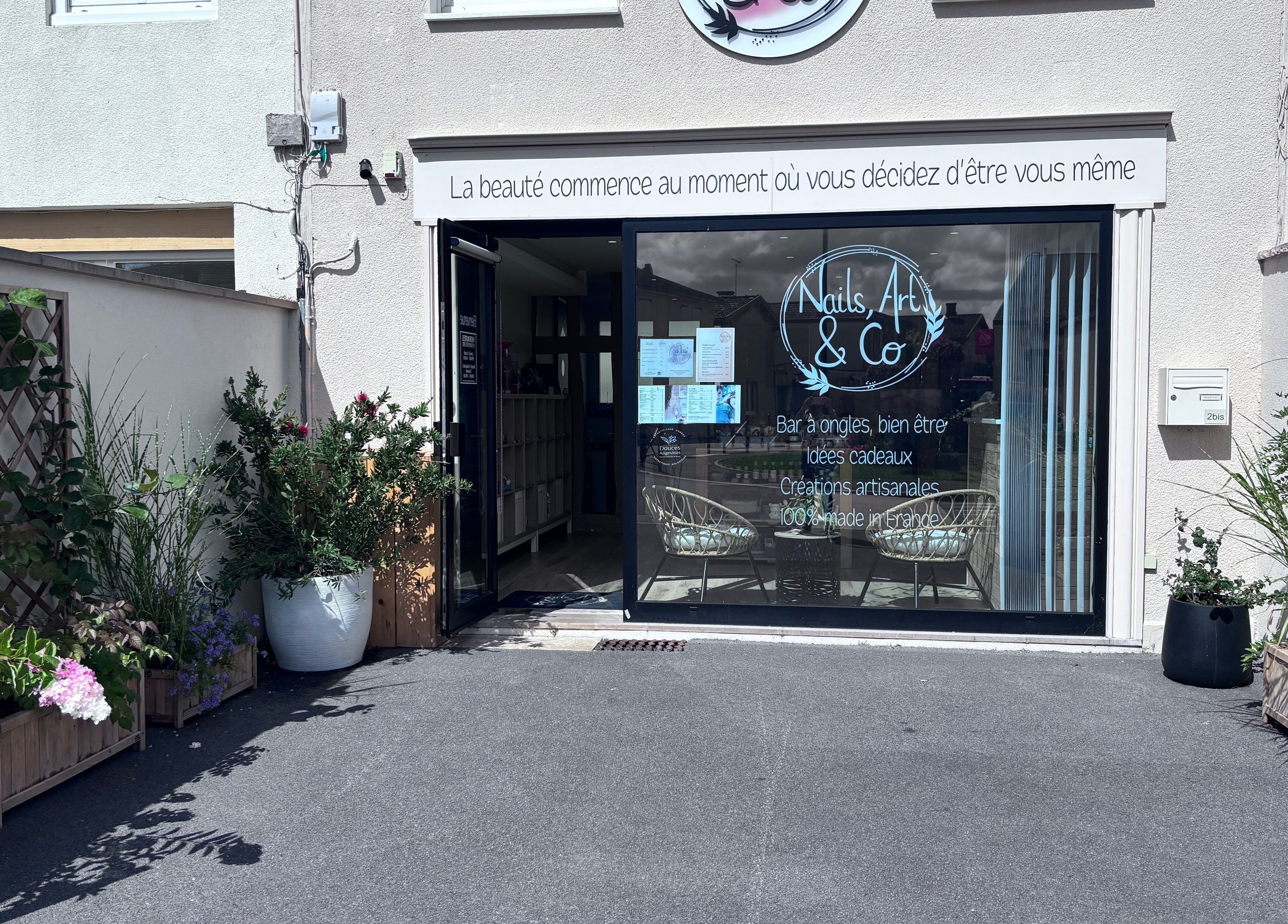 Entrée de Nails, Art & Co à Sarry, Grand Est, FR, entourée de plantes luxuriantes.