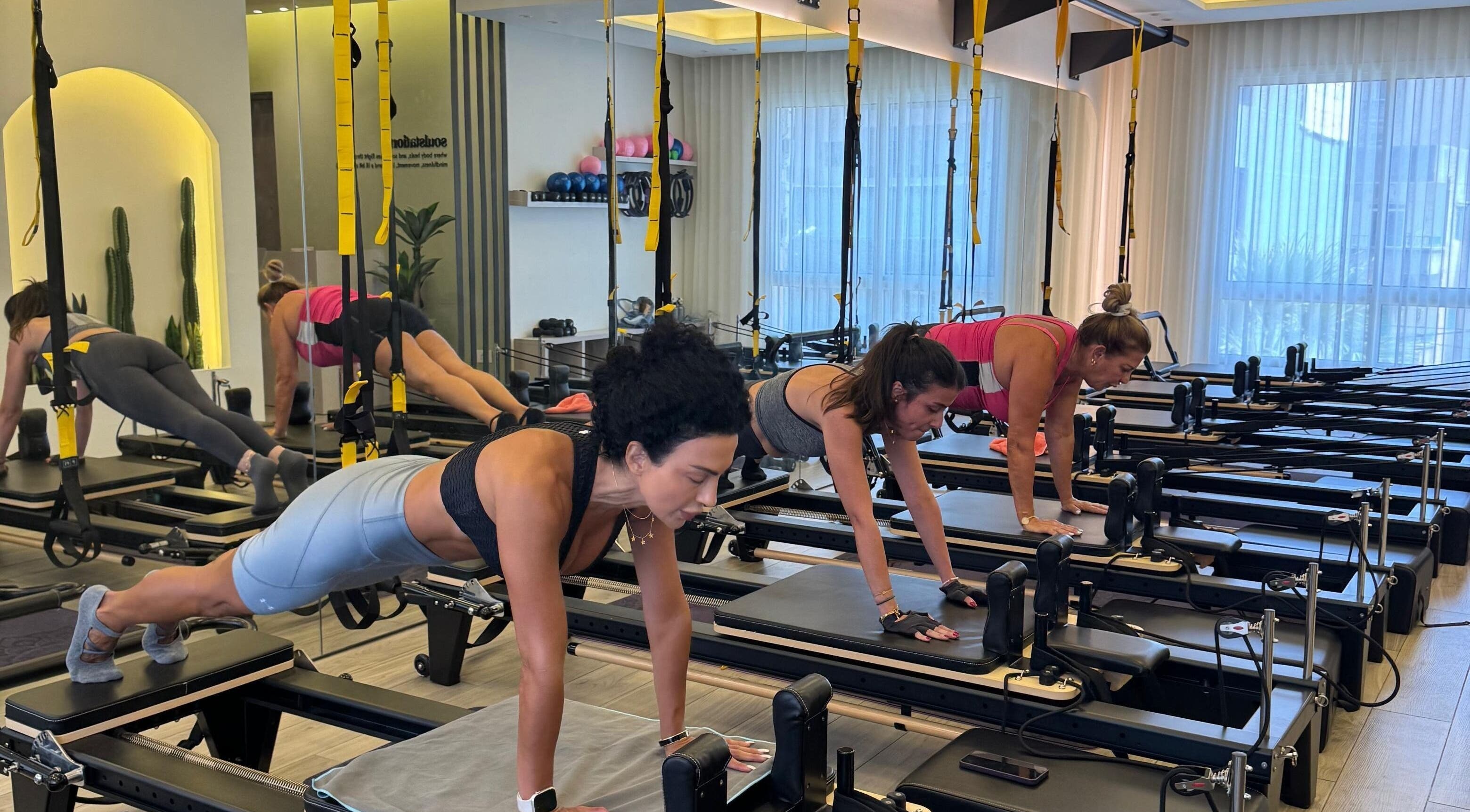Women practicing Pilates at SoulStation Pilates, Zalqa, Mount Lebanon Governorate, LB, in a bright studio.