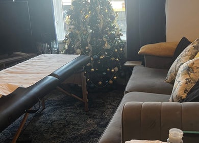 Tranquil massage room at Flutterbrows, Rumney, Wales, GB with cozy decor and a festive tree.