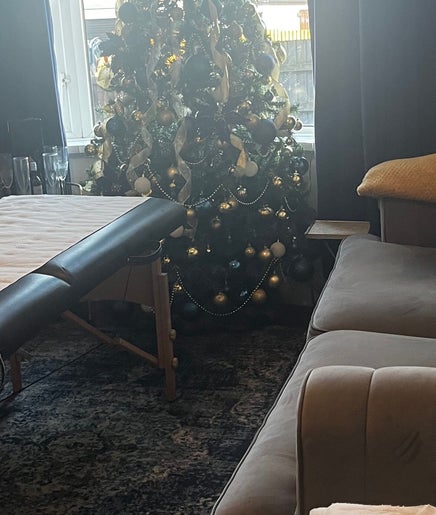 Tranquil massage room at Flutterbrows, Rumney, Wales, GB with cozy decor and a festive tree.