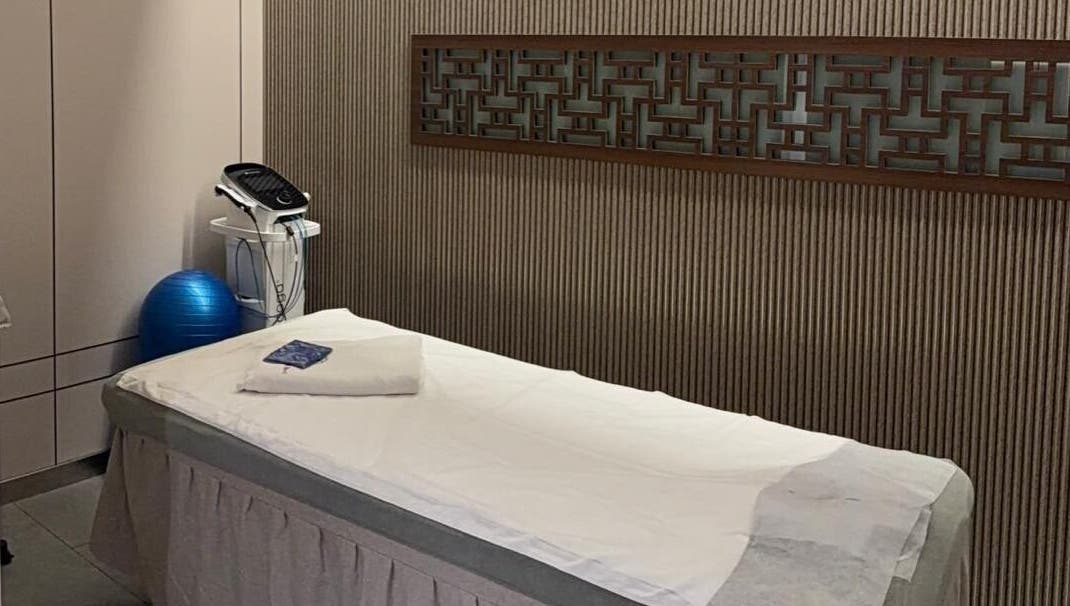 Treatment room at TCM Acupuncture Therapy Center, Dubai, AE, featuring a massage bed and equipment for wellness.