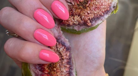 Vibrant pink manicured nails holding a ripe fig at Little Red in London, England, GB.