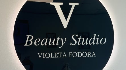Logo Beauty Studio V, Novi Sad, Vojvodina, RS, prikazan na sjajnoj crnoj površini.