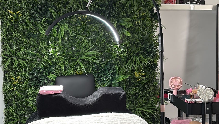 Glambeautybyrosie salon in Carlton, England GB. Modern chair with green wall backdrop and beauty tools.