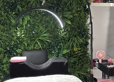 Glambeautybyrosie salon in Carlton, England GB. Modern chair with green wall backdrop and beauty tools.