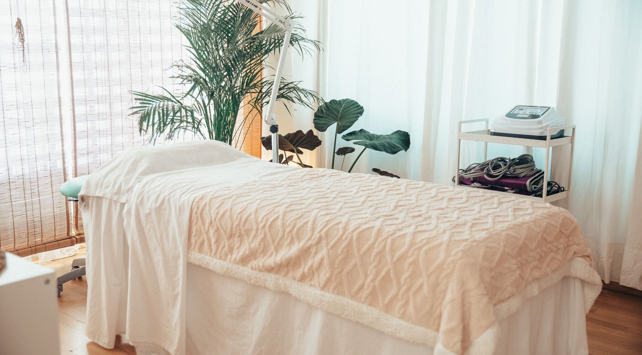 Sala de tratamiento luminosa en Body In Harmony, Rubí, Catalunya, ES con una camilla rodeada de plantas.