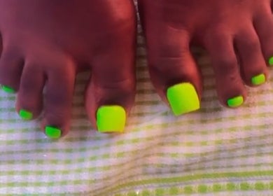 Bright neon green toenails on a checkered towel at The Nail Addict, Bridgetown, Saint Michael, BB.