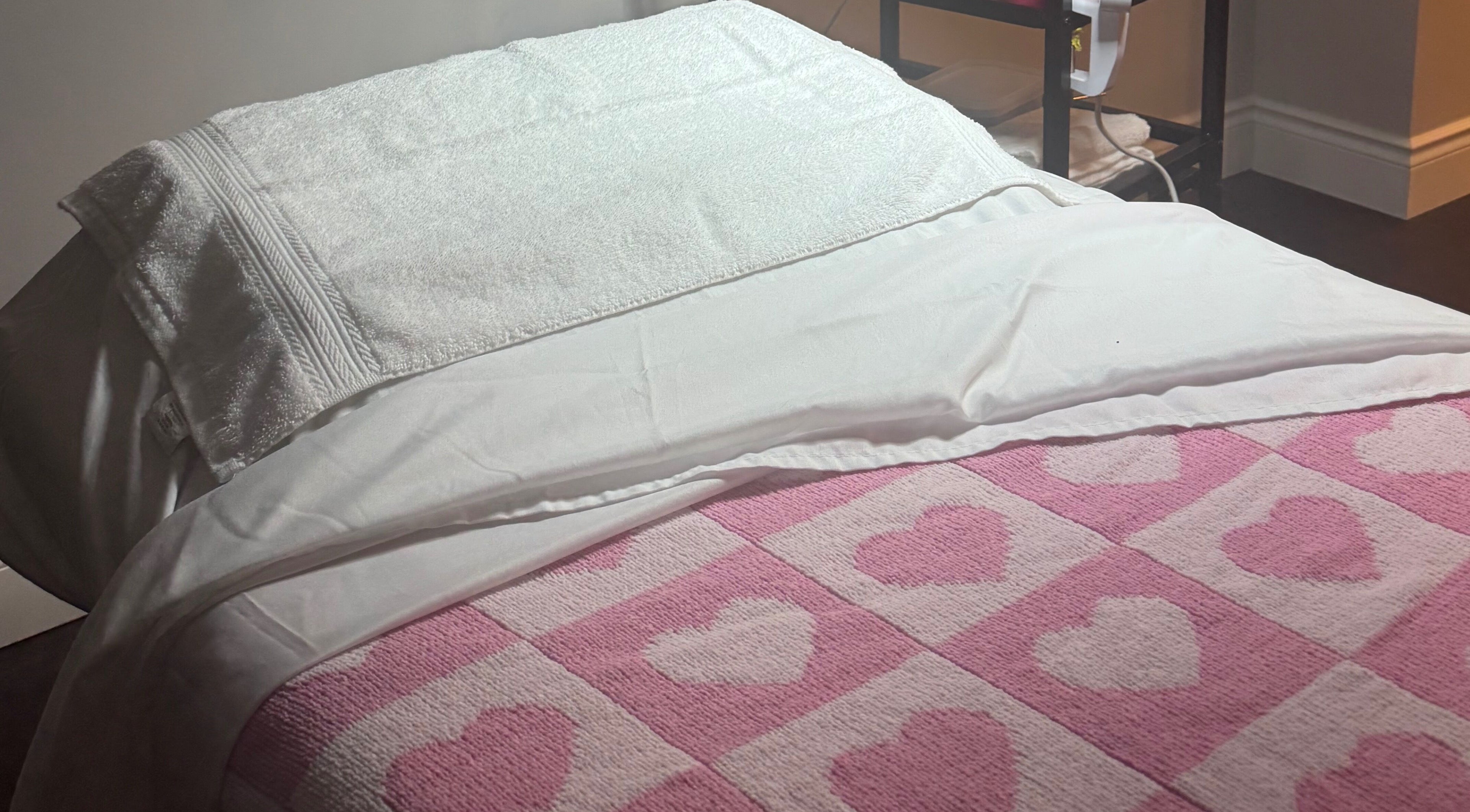 Cozy treatment bed with heart-patterned blanket at The Radiantix Spa in Toronto, Ontario, CA.