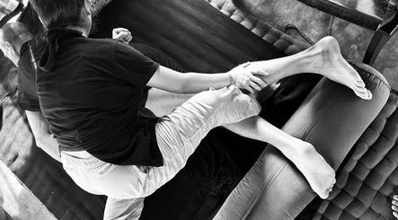A therapist at Muka Concepts X Bambu Indah, Bali, Bali, ID performs a soothing stretch on a client.