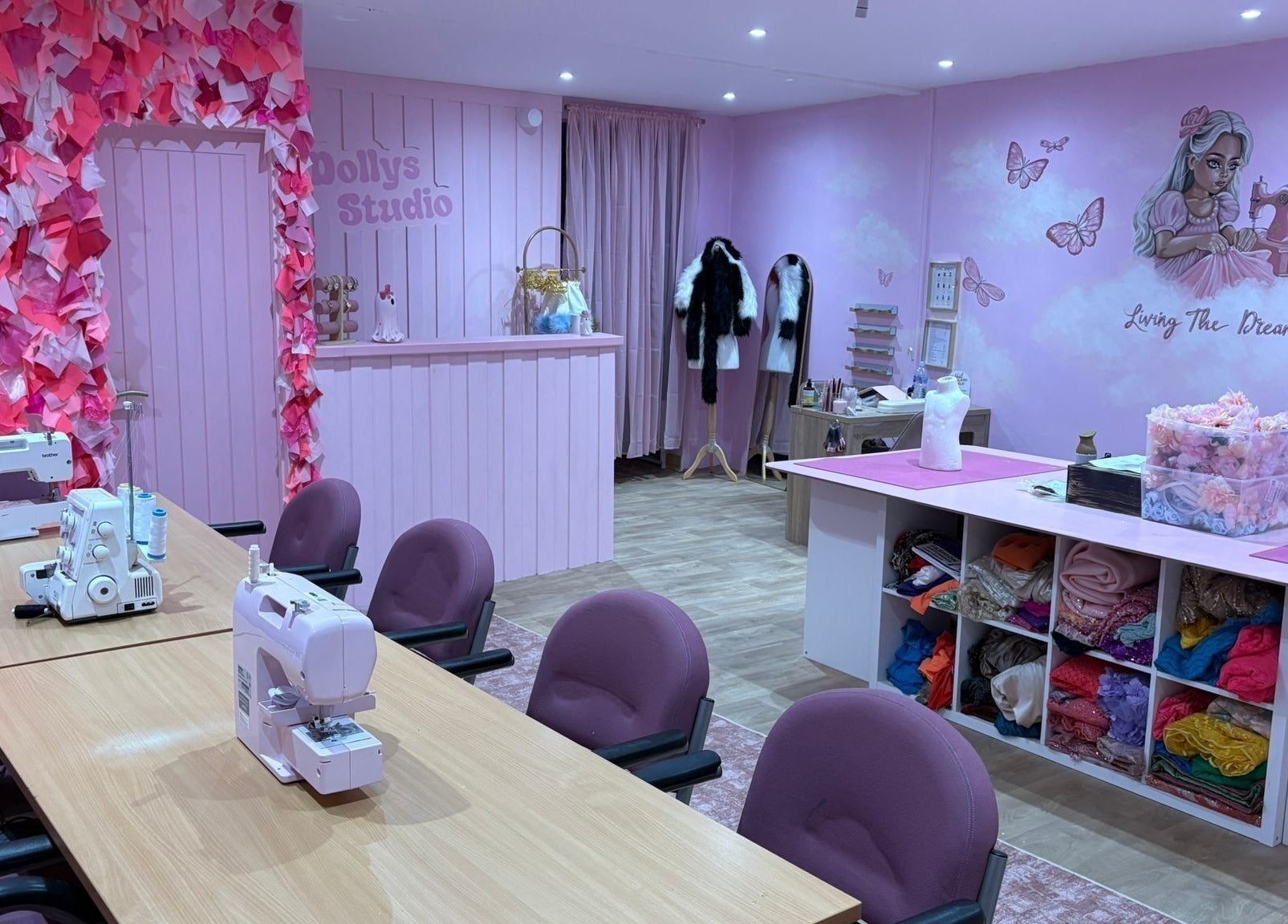 Inside Dolly's Studio in Bradford, England, GB, featuring sewing machines, pink decor, and craft supplies.