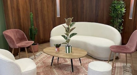 Salon moderne et élégant d'Electraderm à Saint-Denis, Île-de-France, FR avec canapé blanc et chaises roses.