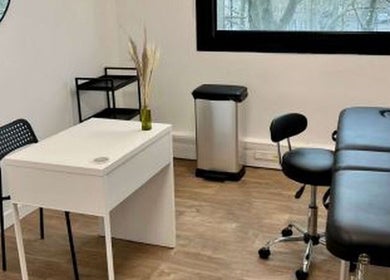 Salle de soin moderne chez Electraderm à Saint-Denis, Île-de-France, FR, avec table de massage et bureau blanc.