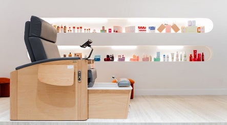 Elegant pedicure chair at Royal Siam Spa in Abu Dhabi, AE, surrounded by beauty products on illuminated shelves.