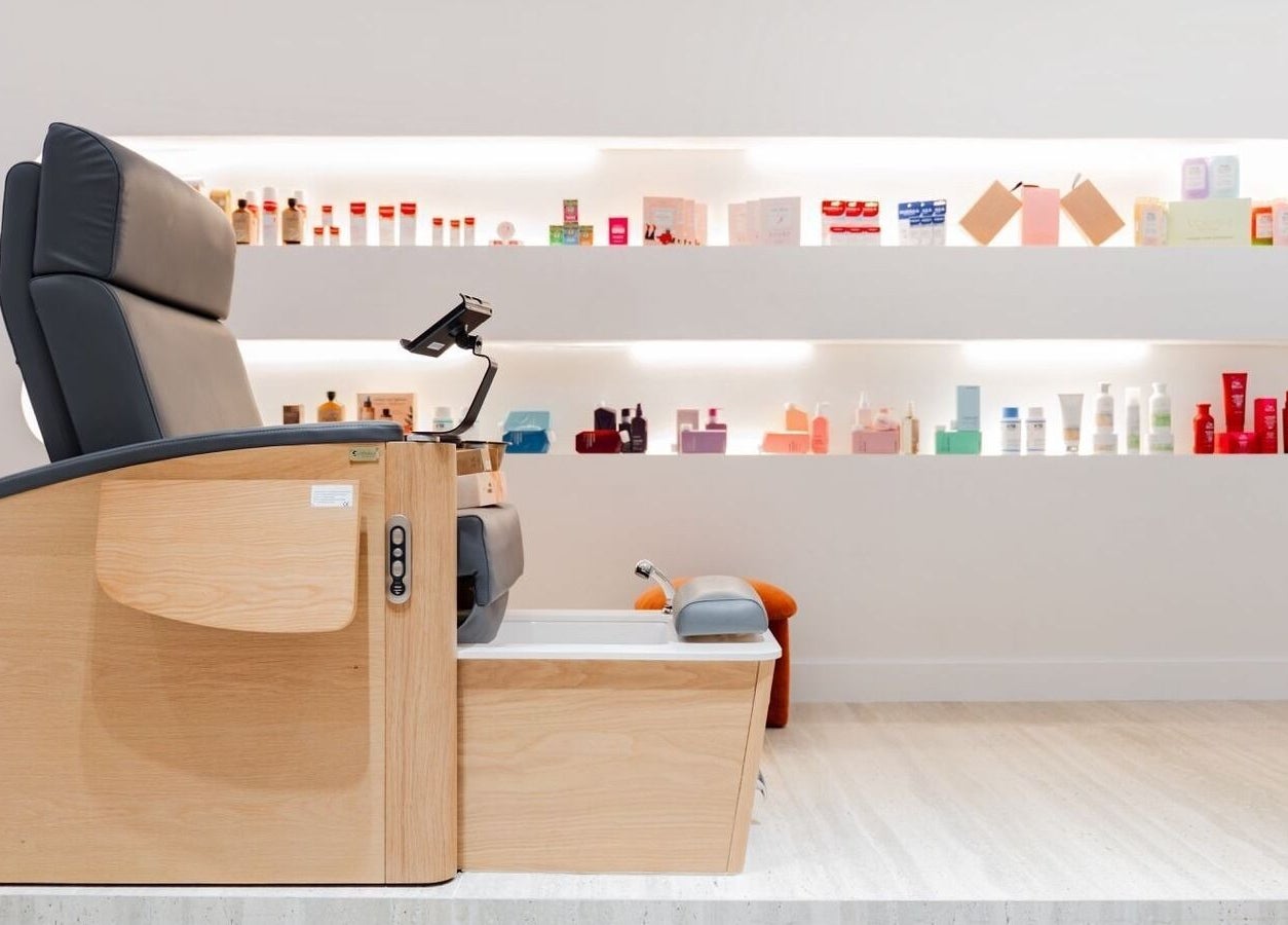 Relaxing pedicure chair at Royal Siam Spa in Abu Dhabi, AE, surrounded by beauty products on illuminated shelves.