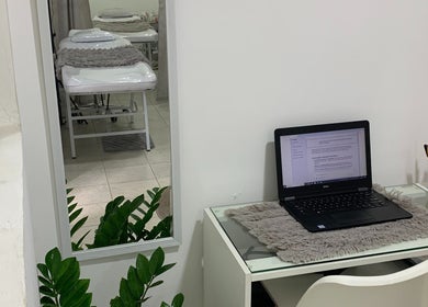 Espacio acogedor en Studio Rose, Valencia, Carabobo, VE. Mesa con laptop y espejo reflejando camillas.