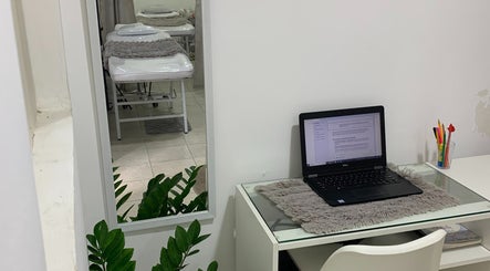 Espacio acogedor en Studio Rose, Valencia, Carabobo, VE. Mesa con laptop y espejo reflejando camillas.