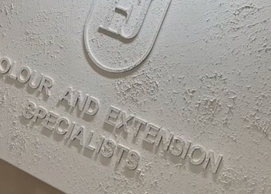 Close-up of a textured signage for Leigh-Anne Hairdressing, Woodbridge, England, GB, specializing in color and extensions.