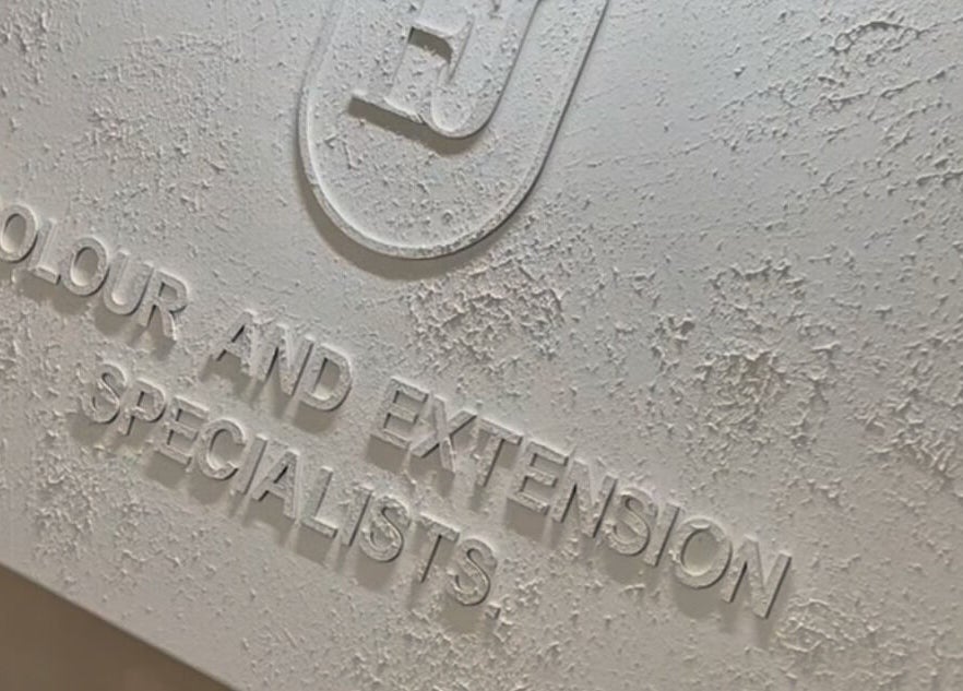 Close-up of a textured signage for Leigh-Anne Hairdressing, Woodbridge, England, GB, specializing in color and extensions.