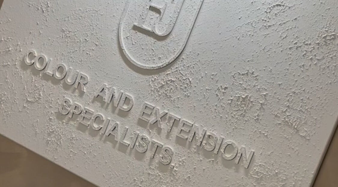 Close-up of a textured signage for Leigh-Anne Hairdressing, Woodbridge, England, GB, specializing in color and extensions.