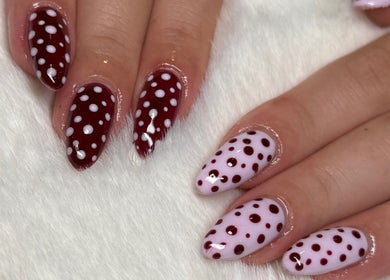 Stylish polka dot nail art by Byabbyrae at Hyde, England, GB, showcasing burgundy and white designs.