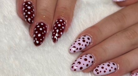 Stylish polka dot nail art by Byabbyrae at Hyde, England, GB, showcasing burgundy and white designs.
