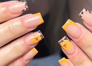 Stylish leopard-patterned acrylic nails with yellow floral tips at JW Beauty, Tyldesley, England, GB.