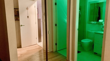 Interior hall with green-lit bathroom at Tension Release Studio, Vancouver, British Columbia, CA.