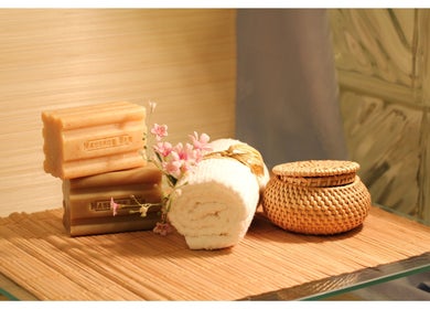 Spa essentials at Tension Release Studio, Vancouver, BC, CA: massage bars, rolled towel, flowers, and wicker jar.