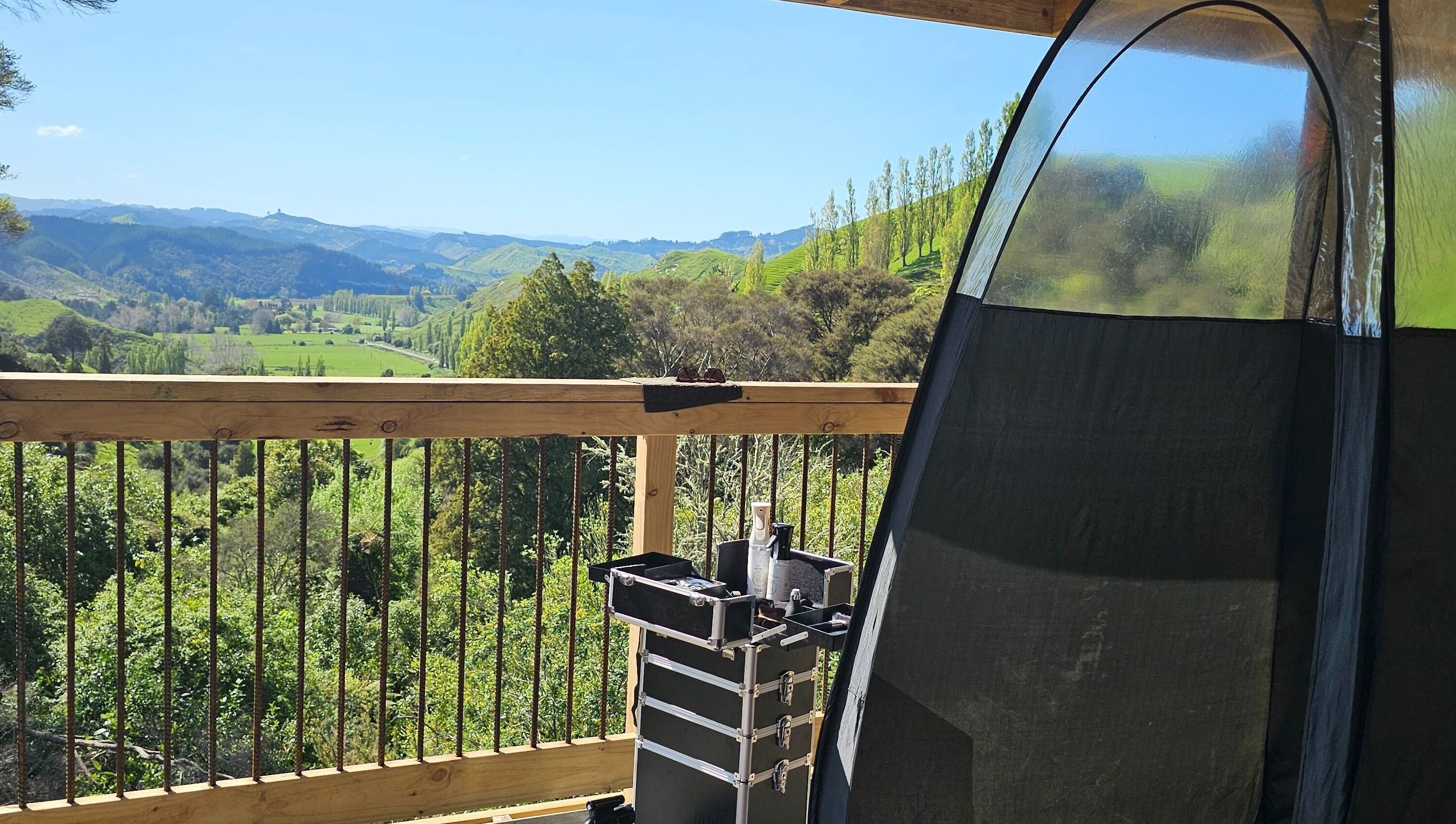 Outdoor tanning setup at Tan Acres Mobile Spray Tanning, Whanganui, with a lush green valley view.