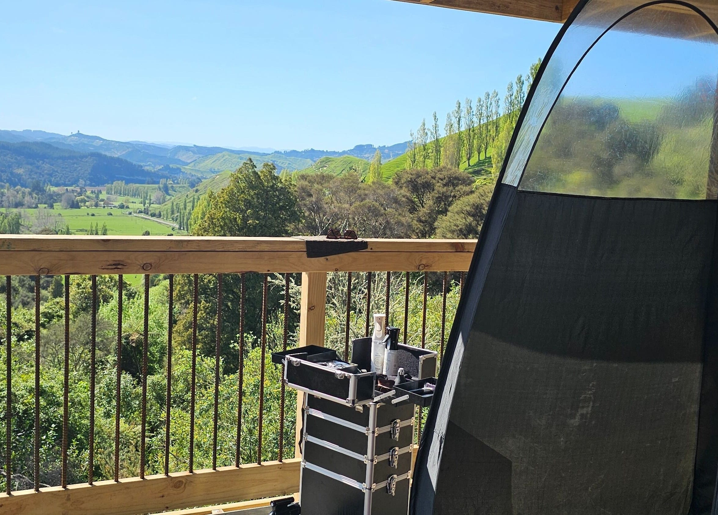 Outdoor tanning setup at Tan Acres Mobile Spray Tanning, Whanganui, with a lush green valley view.