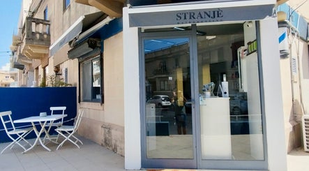 Front view of Stranjé Hairdressing in Ħ'attard, MT, featuring elegant storefront and outdoor seating.
