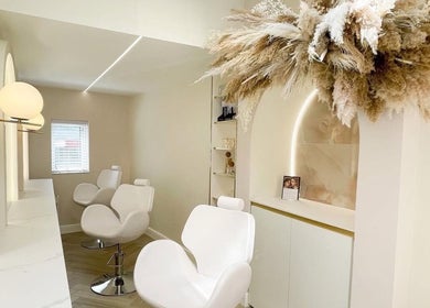 Luxurious beauty salon interior at By Élize, Plymouth, England, GB with plush white chairs and modern decor.
