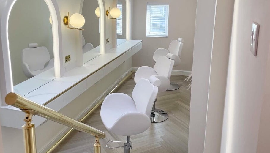 Chic salon setup at By Élize, Plymouth, England, GB featuring plush white chairs and stylish lighting.