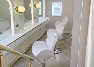 Chic salon setup at By Élize, Plymouth, England, GB featuring plush white chairs and stylish lighting.