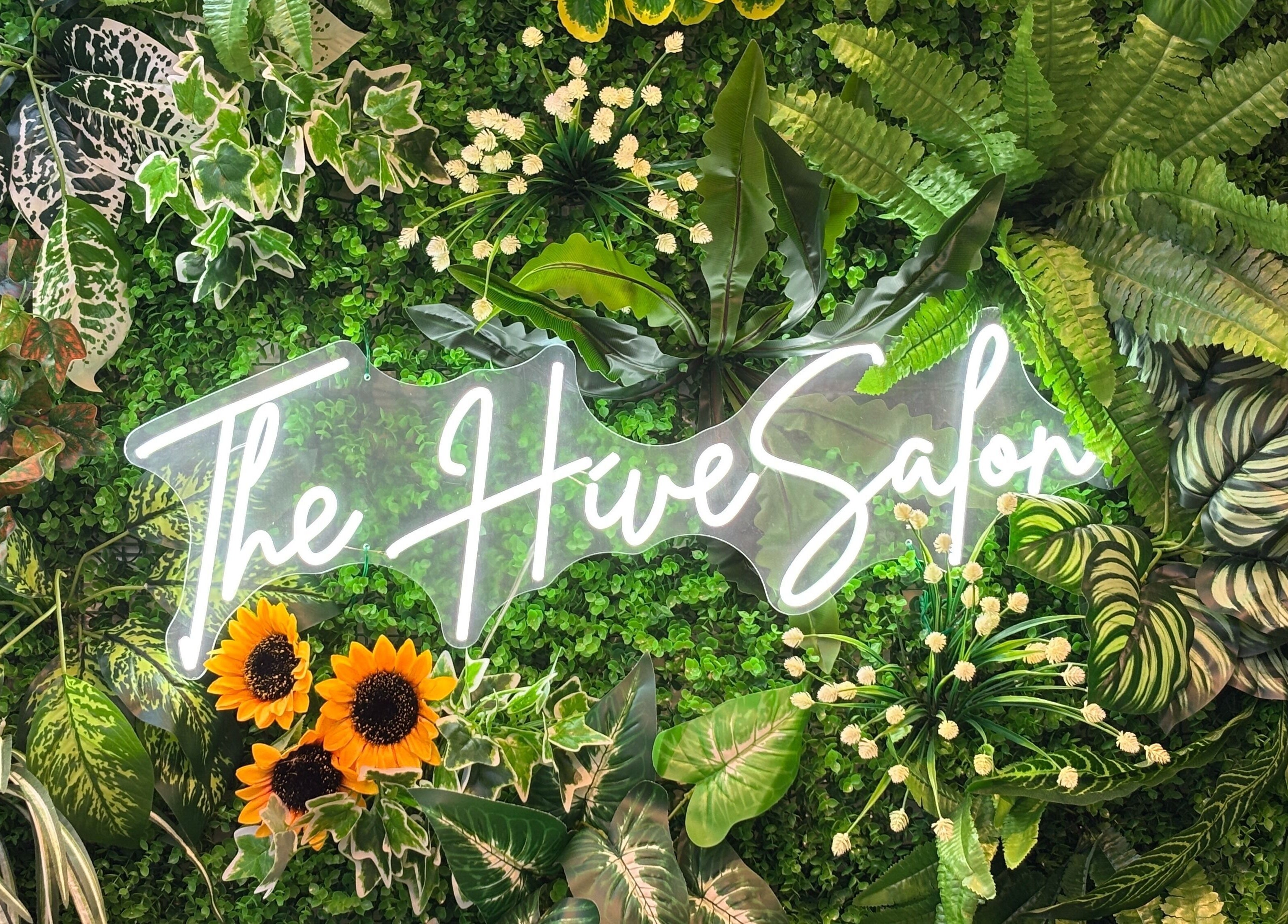 Lush greenery backdrop with 'The Hive Salon' sign in Singapore, Singapore, SG.