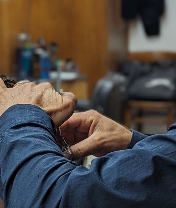 A barber at Wick Lane Barbershop in London, England, GB expertly styling a client's hair.