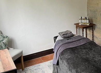 Cozy massage room at The Serenity Lodge, Long Marston, England, GB, featuring a plush treatment bed and ambient decor.