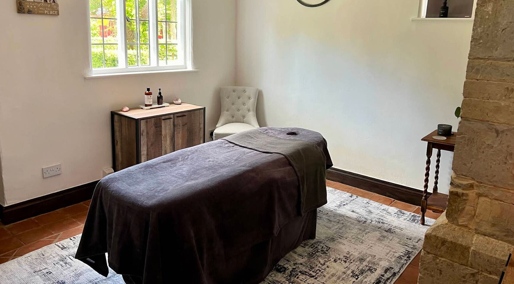 Massage room at The Serenity Lodge, Long Marston, England, GB, featuring a cozy table and soft lighting.