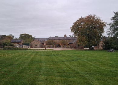 Charming rustic venue, The Sanctuary at Upper Farm, in Tiffield, England, GB with lush green lawn and trees.