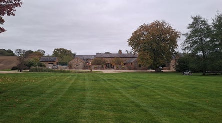 Charming rustic venue, The Sanctuary at Upper Farm, in Tiffield, England, GB with lush green lawn and trees.