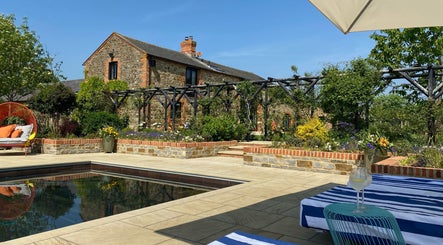 Relax by the pool at The Sanctuary at Upper Farm, Tiffield, England, GB, surrounded by lush greenery.