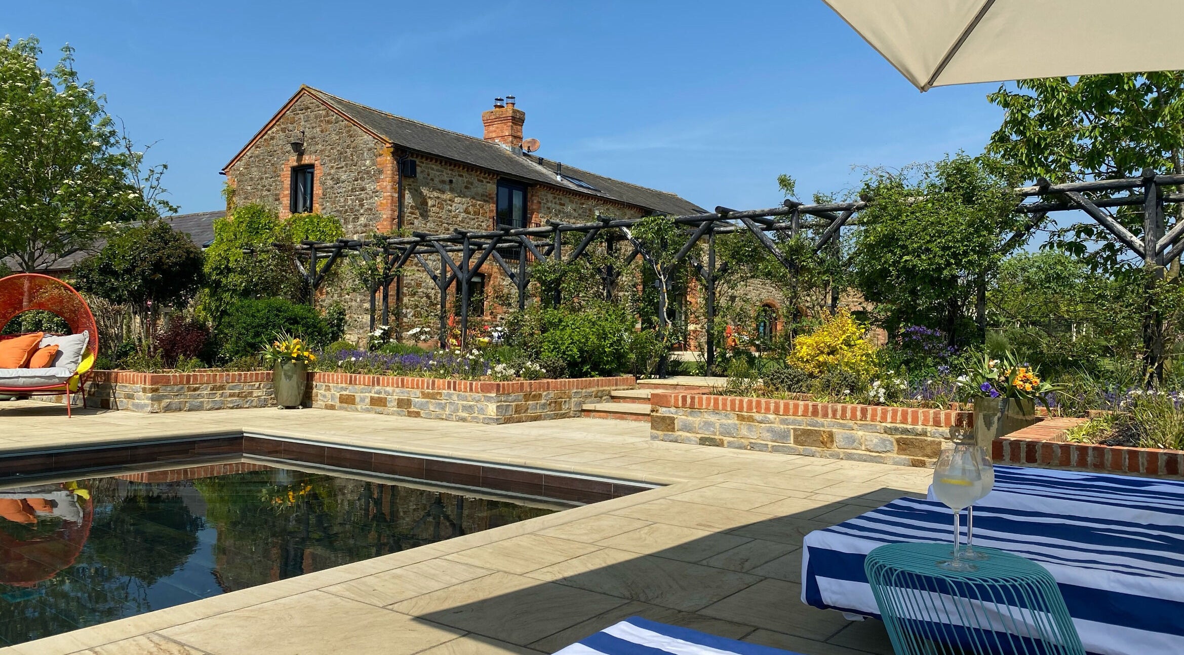 Relax by the pool at The Sanctuary at Upper Farm, Tiffield, England, GB, surrounded by lush greenery.