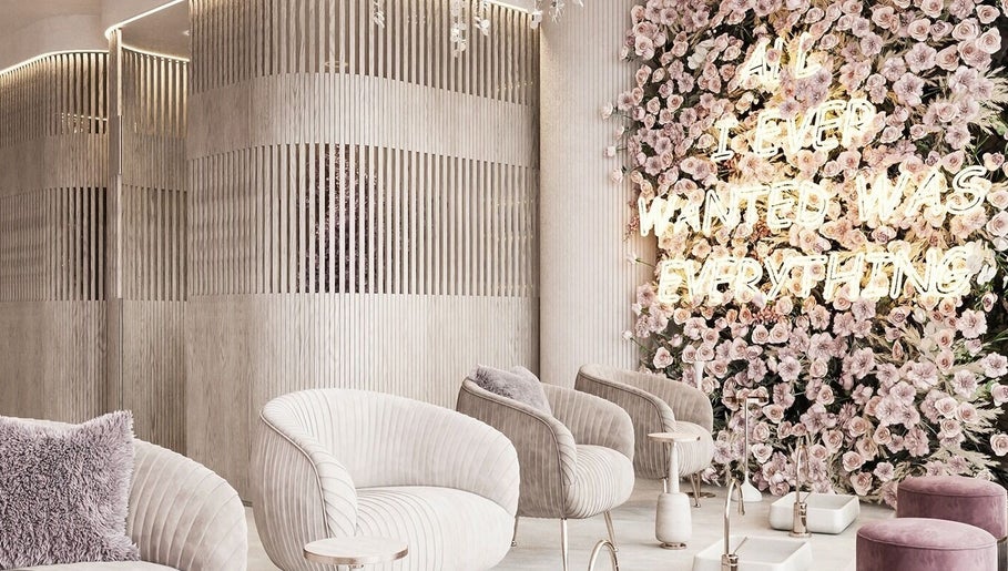 Elegant waiting area at iBrows by Farah, Coventry featuring floral wall and plush seating in a modern design.