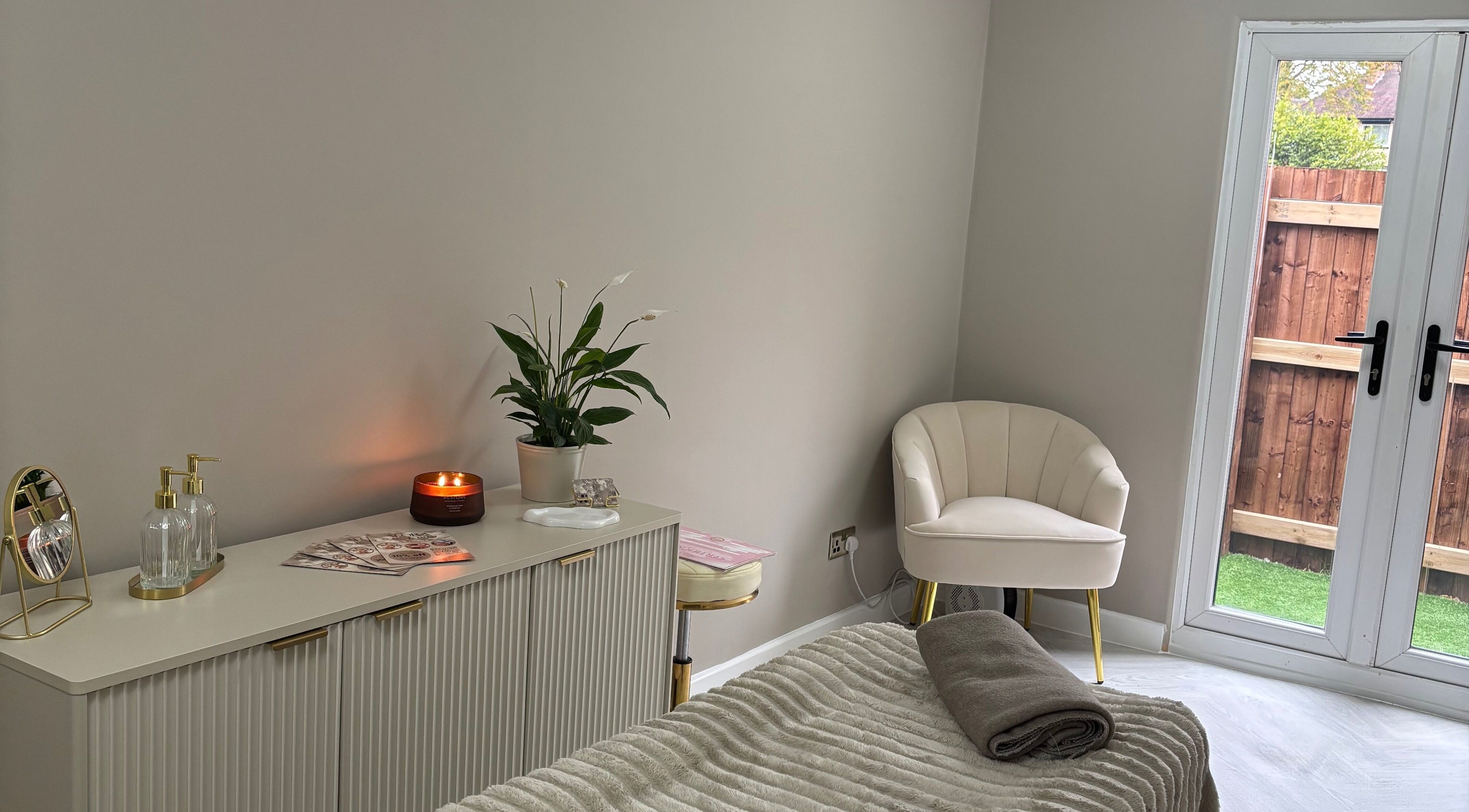 Relaxing treatment room at Alora SkinSpecialist, Birmingham, England, GB, featuring cozy chair and ambient lighting.